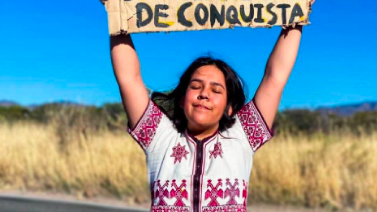 Wixárika Scholarship Fund recipient, María Fernanda Ramírez Gamboa, with a sign that says, "Neither the land nor women are territories to be conquered."